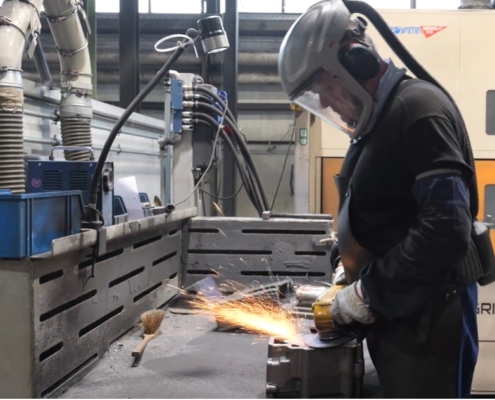 Mann steht an Werkbank, trägt gebläsegestützen Atemschutz